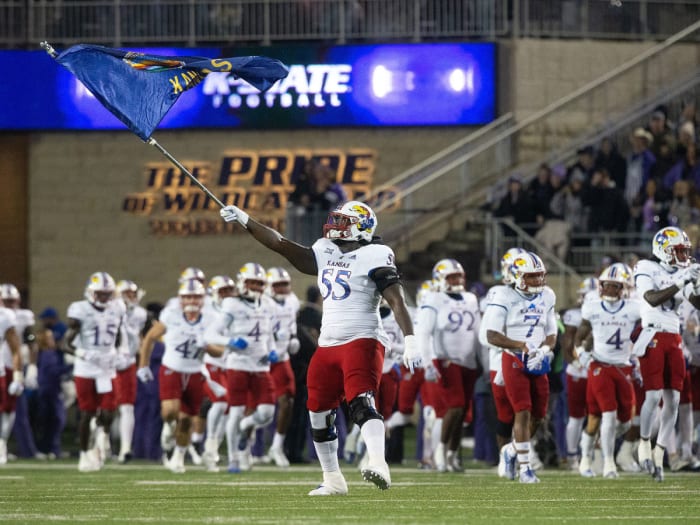 A Kansas football player waves a Jayhawks flag